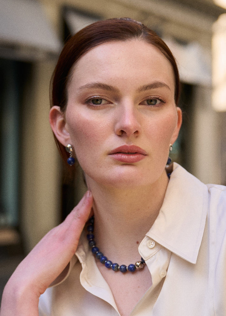 Woman wearing a blue beaded necklace with a blurred background