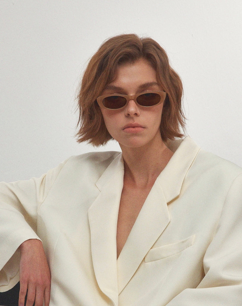Person wearing a white blazer with a deep neckline against a plain background