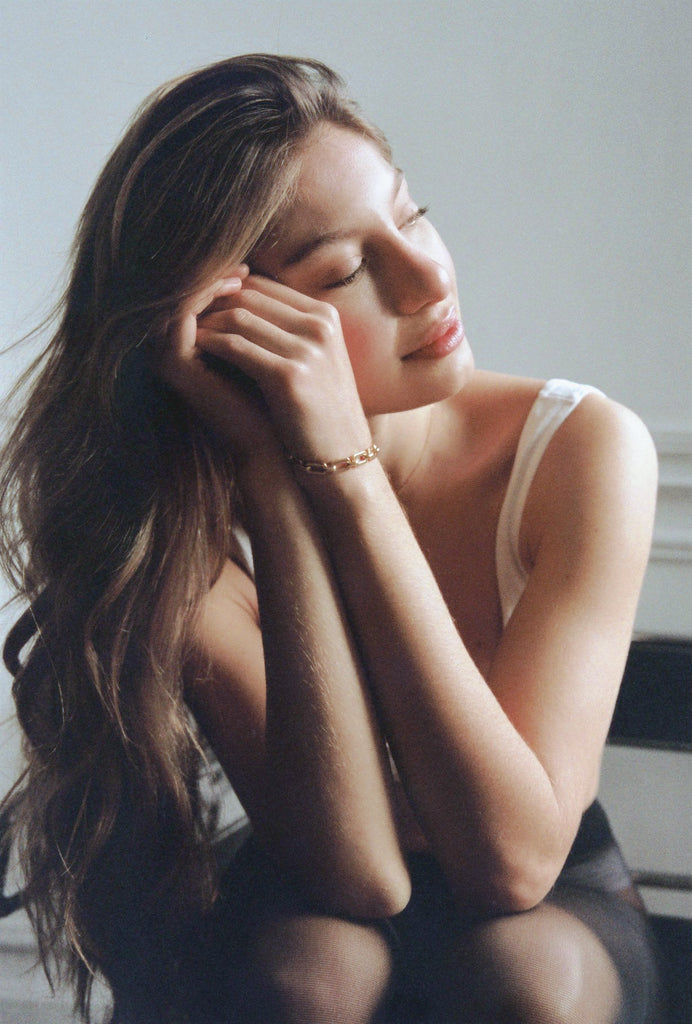 Woman sitting with her hand on her face in a softly lit room