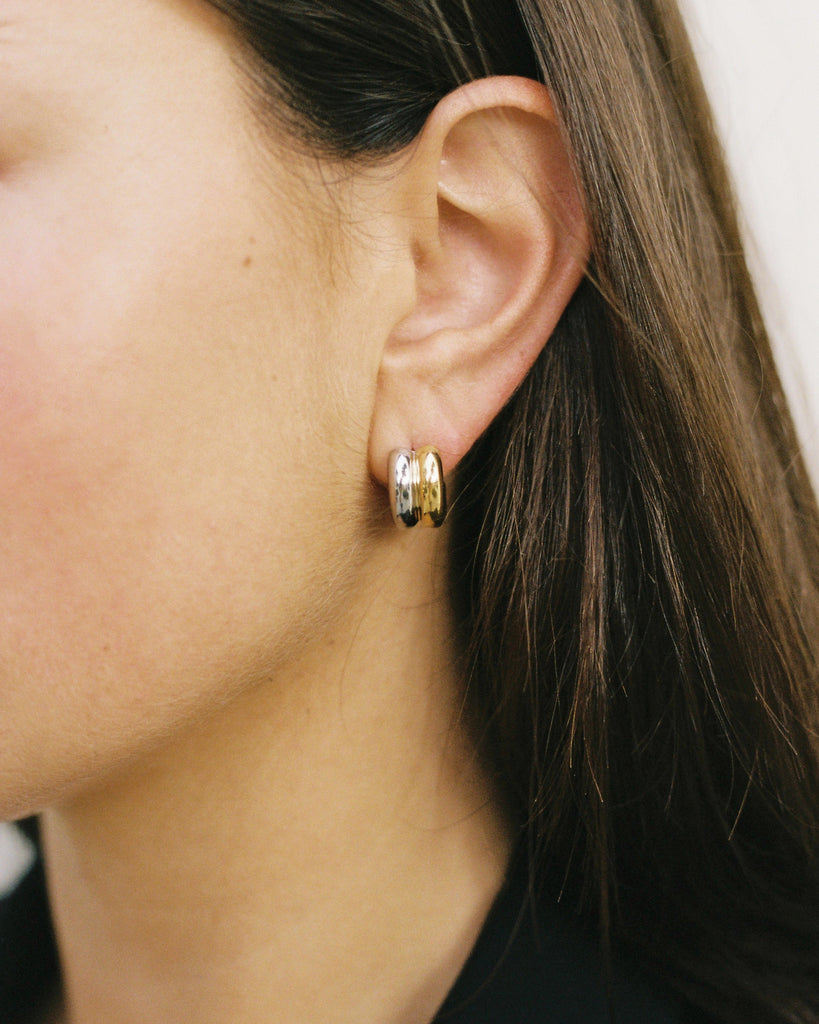 Close-up of an ear wearing gold hoop earrings with a blurred background